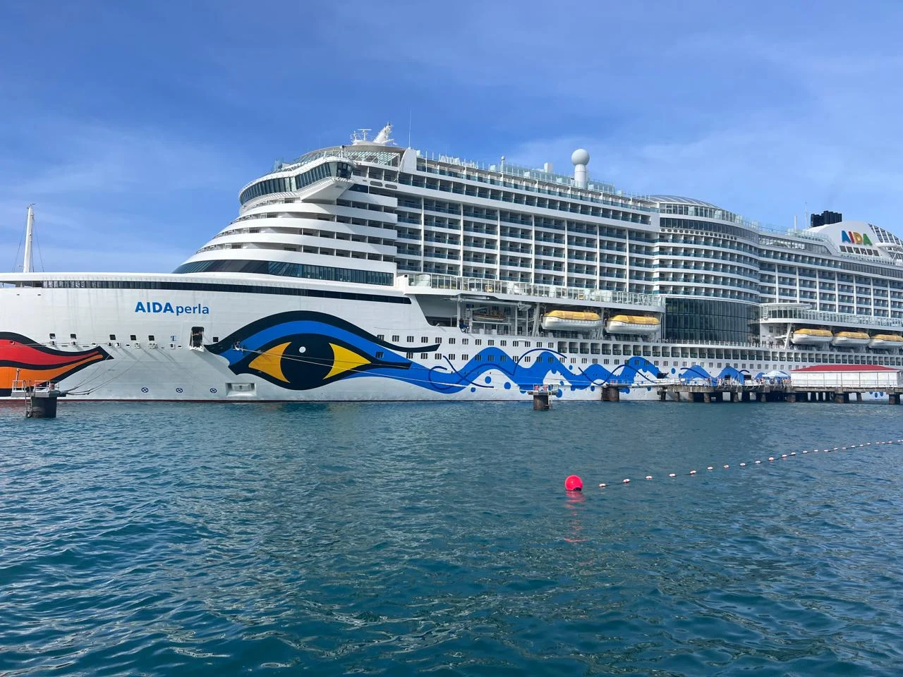 A white cruise ship with colourful artwork on its hull beside the waterfront