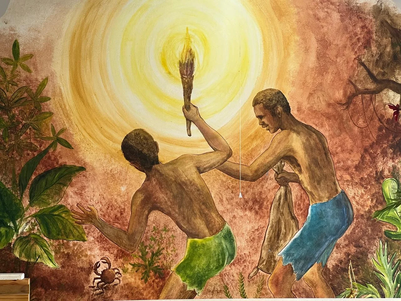A mural in warm golden tones showing two figures with a torch among tropical plants