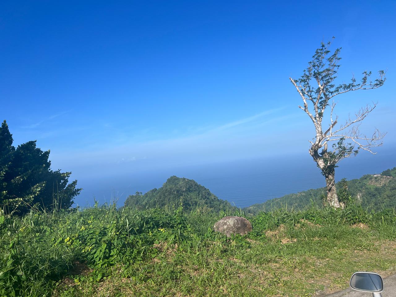 Green mountains and the ocean seen from a mountain road
