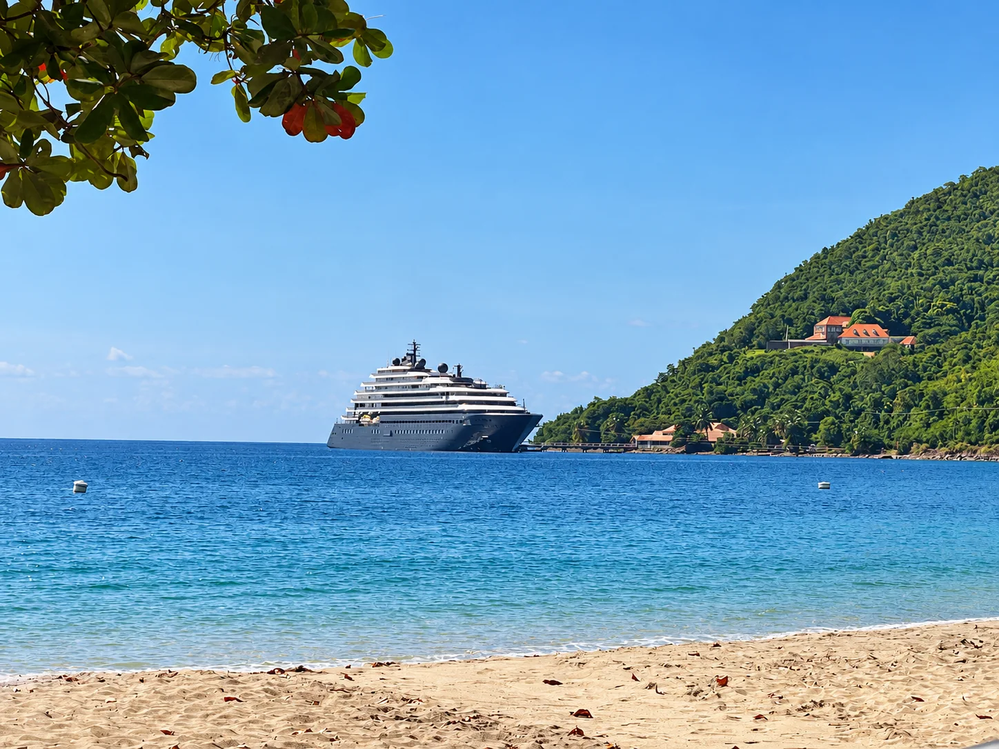 A quiet bay with a beach, a green headland and a ship